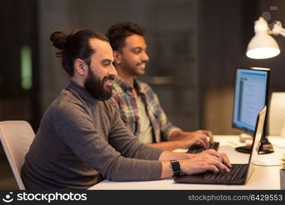 deadline, technology and people concept - creative team s with computers working late at night office. creative team with computers working at office