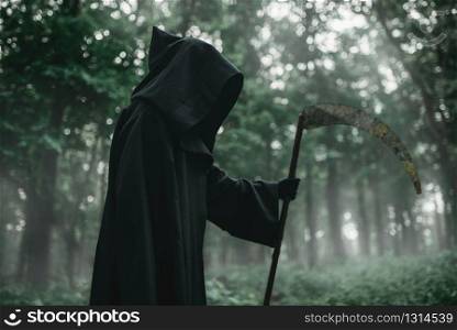 Death in a black hoodie and with a scythe in forest. Horror style, fear, spooky evil. Death in a black hoodie with a scythe in forest