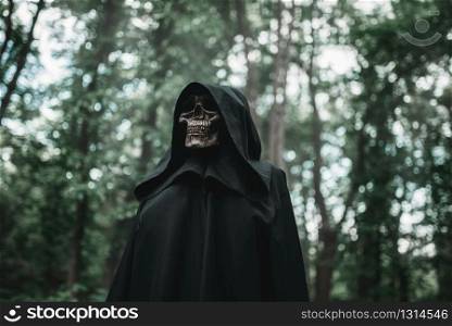 Death in a black hoodie in forest. Horror style, fear, spooky evil. Death in black hoodie in forest