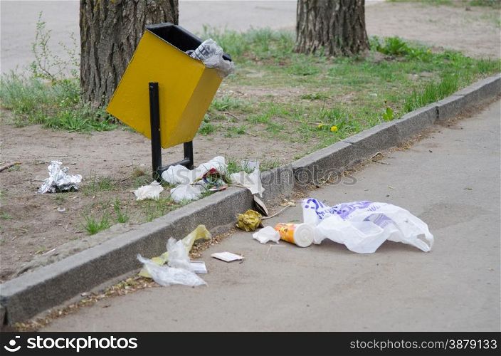 Debris is scattered around the garbage bins on a city street. Debris is scattered around the garbage bins