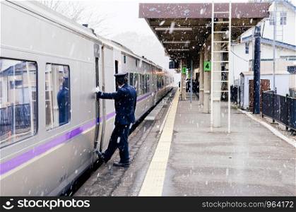 DEC 1, 2018 Hakodate, JAPAN - JR Suoer Hokuto train stop at Onuma Koen station platform during snow fall in winter with train conductor staff stand at trian door.