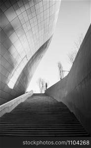 DEC 11, 2015 Seoul, South Korea - Dongdaemun design plaza or DDP modern free from building architecture in black and white with metalic facade and long entrance stair by Zaha Hadid