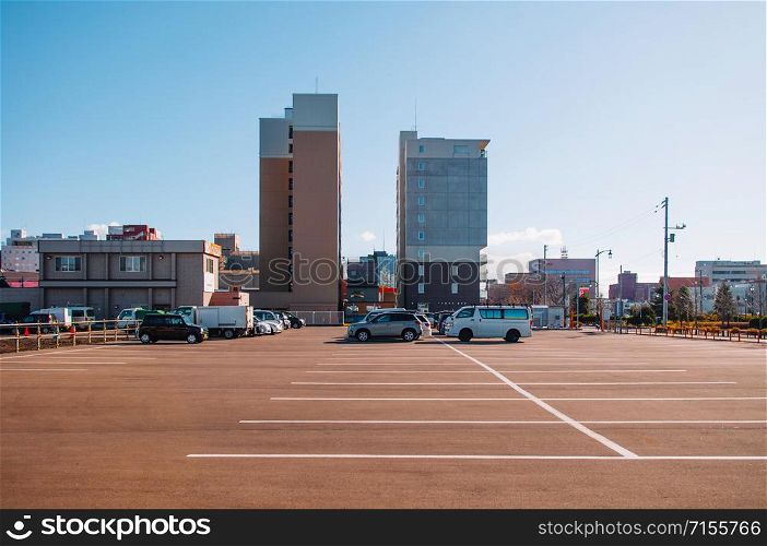 DEC 2, 2018 Hakodate, Japan -Car parking lot Public parking in the city with many empty space under clear blue sky with buildings background.
