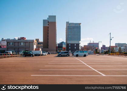 DEC 2, 2018 Hakodate, Japan -Car parking lot Public parking in the city with many empty space under clear blue sky with buildings background.