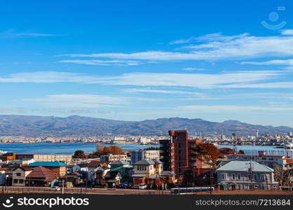 DEC 2, 2018 Hakodate, JAPAN -Hakodate blue harbour bay and cityscape residential buildings with mountain view and blue sky. Seen from Motomachi park in winter