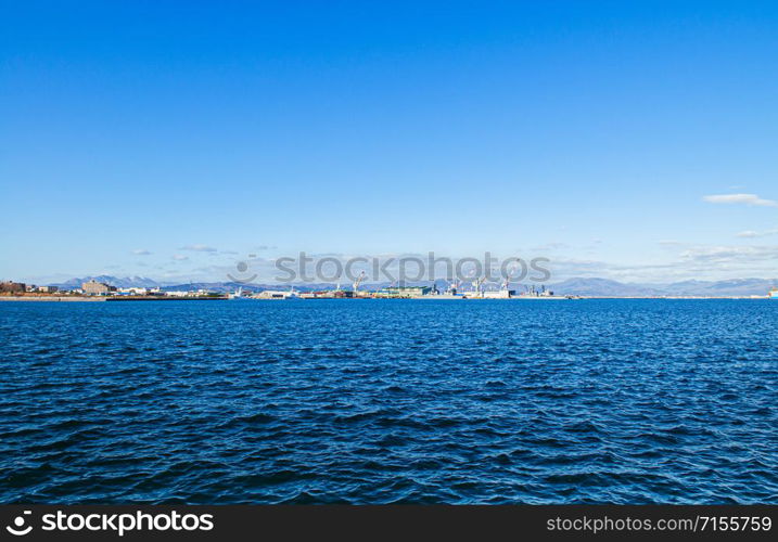 DEC 2, 2018 Hakodate, JAPAN -Hakodate blue harbour bay and industrial port with large cranes and ship mountain view background, Distant view.