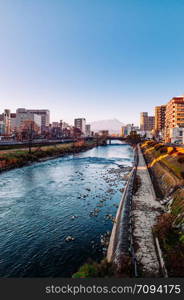 DEC 2, 2018 Iwate, Japan - Mount Iwate Morioka city scene with buildings and promenade at Katakami river with warm sunset light clear sky in winter - Tohoku region beautiful landscape