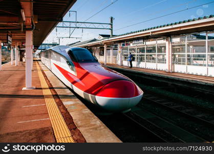 DEC 3, 2018 Kakunodate, Japan - Akita Komachi Shinkansen E6 Series vibrant modern red body at Kakunodate JR station platform with beautiful sunlight in autumn