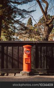 DEC 3, 2018 Kakunodate, Japan - Red vintage Japanese mail letter postbox and black wooden wall in Kakunodate old Samurai town of Akita, Tohoku region