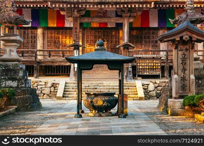 DEC 3, 2018 Yamagata, Japan - Konponchudo main hall inscent pot in Yamadera Risshaku ji temple with old wood wall and colourful Buddhism flags