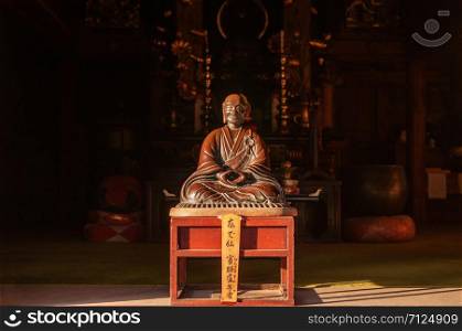 DEC 3, 2018 Yamagata, Japan - Nenbutsu hall old wooden Buddha monk statue on wood table under warm evening light in Yamadera Risshaku ji temple