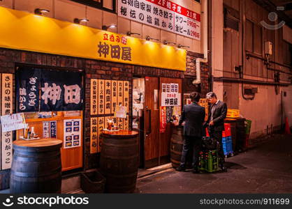 DEC 4, 2018 Tokyo, Japan - Izakaya bar and night street restaurant with neon signs and local people in front of Kanda JR station