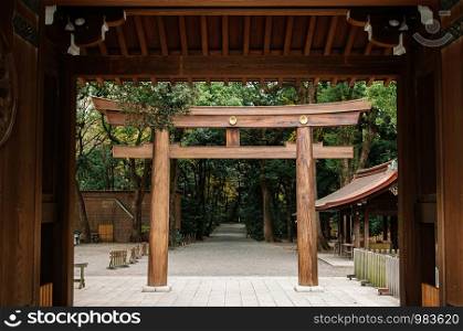 DEC 5, 2018 Tokyo, Japan - Meiji Jingu Shrine Historic Wooden Torii gate seen through old gate entrance - Most important shrine and city green space of Japan capital city.