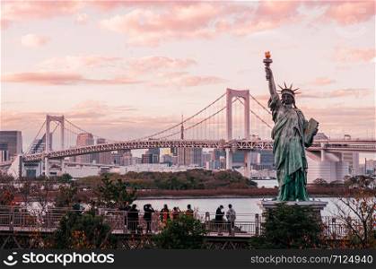 DEC 5, 2019 Tokyo, Japan - Odaiba Rainbow bridge and Tokyo bay view with tourists enjoy evening sunset with cityscape in background under warm tone sky