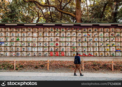 DEC 5, 2019 Tokyo, Japan - Sake Barrels wall or Kazaridaru of Meiji Jingu Shrine under big tree with tourist walking pass. Use as a gift to Shinto god from business company.