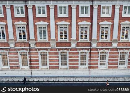 DEC 6, 2019 Tokyo, Japan - Tokyo Station historic red brick building wall facade and beautiful window with people walking on sidewalk aerial view