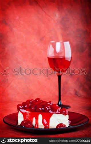 Decadent cherry cheesecake served on a candy apple red plate with red wine,on a red background.
