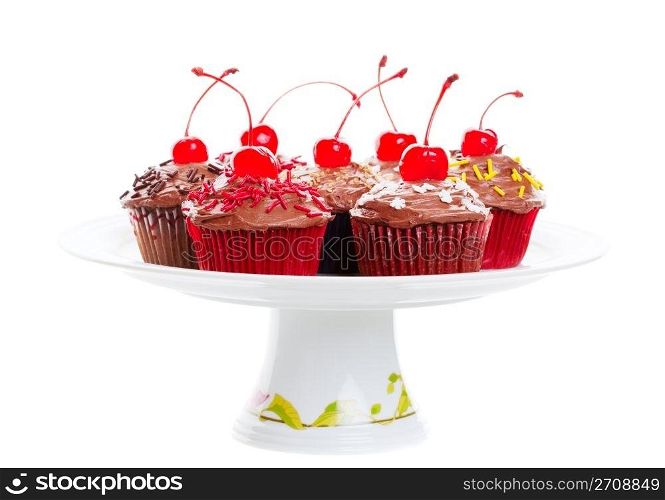 Decadent chocolate cherry cupcakes arranged on a pedestal cake plate. Shot on white background.