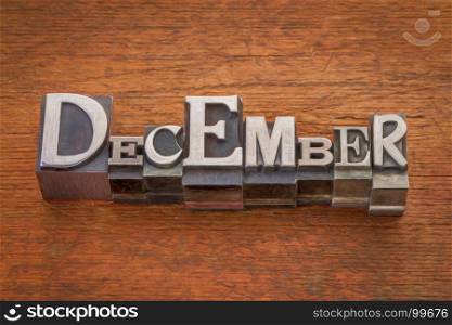 December word in mixed vintage metal type printing blocks over grunge wood with a digital painting filter applied