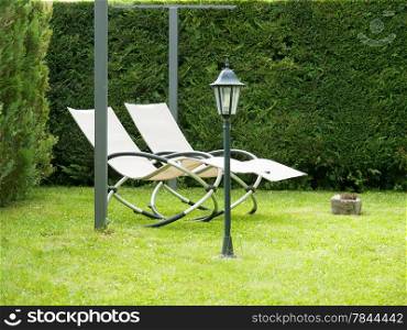 deck chair on green grass surrounded with hedge
