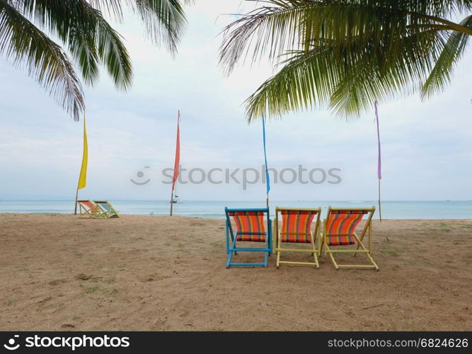 deck chair under a palm-tree on a tropical beach