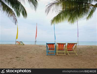 deck chair under a palm-tree on a tropical beach