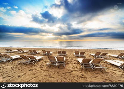 deck chairs on the beach at sunrise