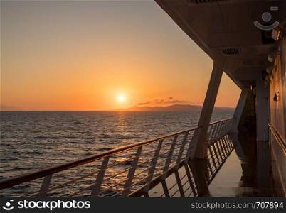 Deck on small cruise liner sailing across the ocean as the sun rises. Cruise ship sailing the seas at sunrise or dawn