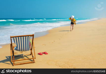 Deckchair and woman in white sunhat going along the beach .Vacation and travel concept.
