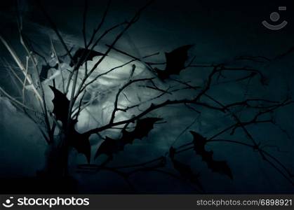 Decor of the silhouettes of bats on branches in a web in the night haze.