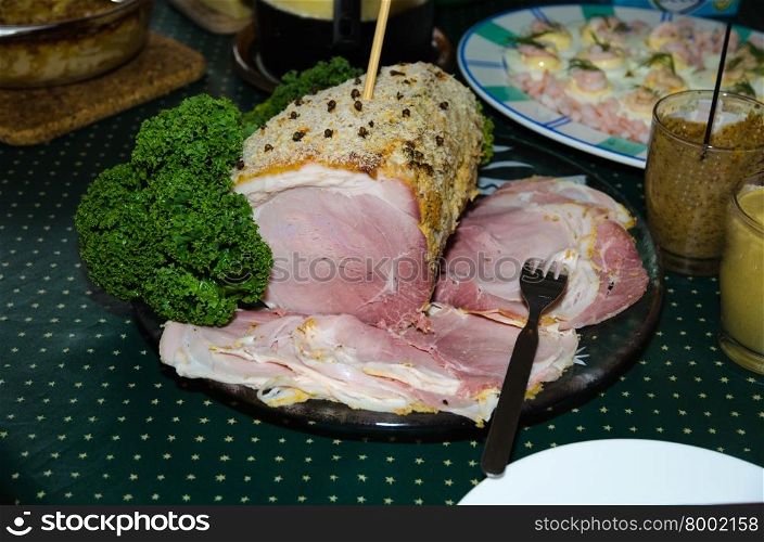 Decorated and sliced christmas ham on a plate at a table