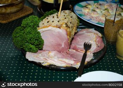 Decorated and sliced christmas ham on a plate at a table