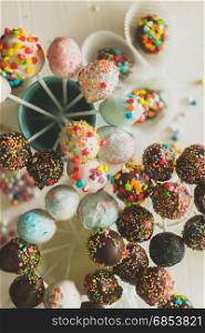 Decorated cake pops and candies on table