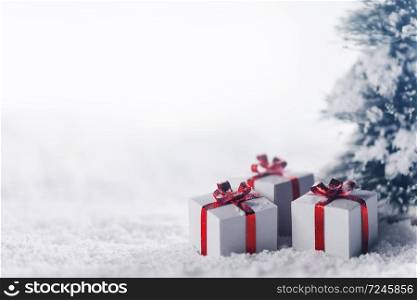 Decorated christmas gifts under fir tree on snow , background with copy space. Gift boxes in snow under tree