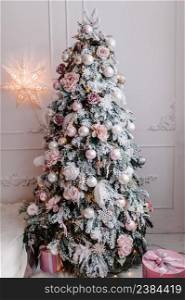Decorated Christmas interior. Fir-tree decorated garlands with gifts boxes in a white room. Decor. Happy New Year and Merry Christmas. The concept of winter holiday.