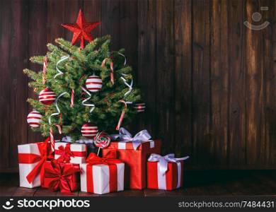 Decorated Christmas tree and gift boxes on wooden background. Decorated Christmas tree