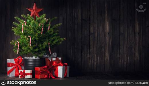 Decorated Christmas tree. Decorated Christmas tree with candy canes and gift boxes on wooden background