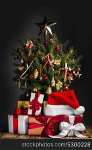 Decorated Christmas tree. Decorated Christmas tree with glowing lights and gift boxes on dark background