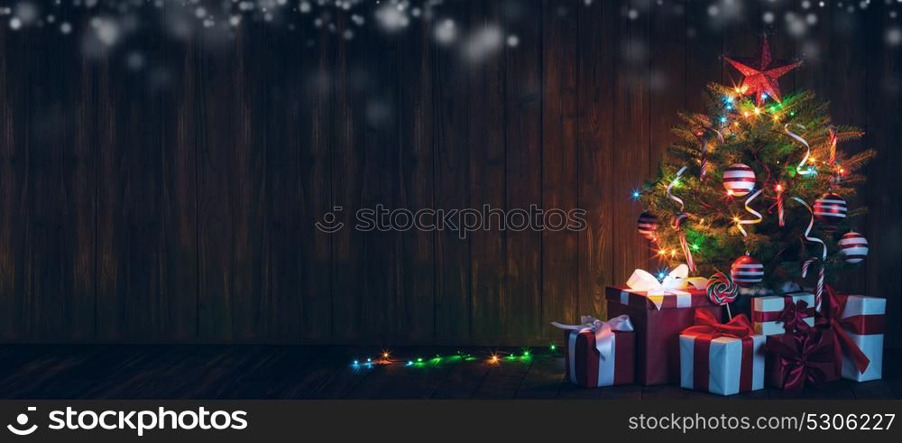 Decorated Christmas tree. Decorated Christmas tree with glowing lights and gift boxes on wooden background