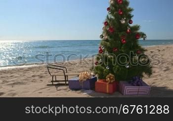 Decorated Christmas tree with gift boxes on a sandy beach