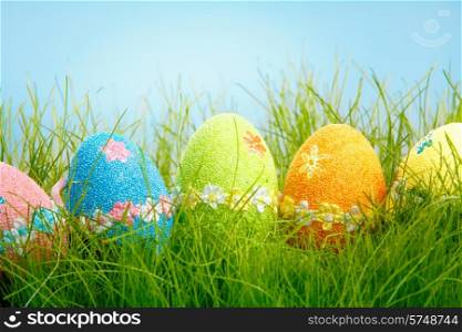 Decorated easter eggs in the grass on blue background