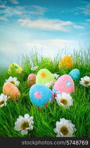 Decorated easter eggs in the grass on blue background