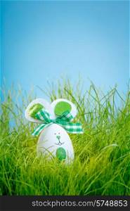 Decorated easter eggs in the grass on blue background