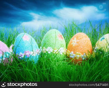 Decorated easter eggs in the grass on blue sky background