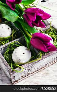 Decorated Easter eggs in wooden box with straw,is decorated with tulips