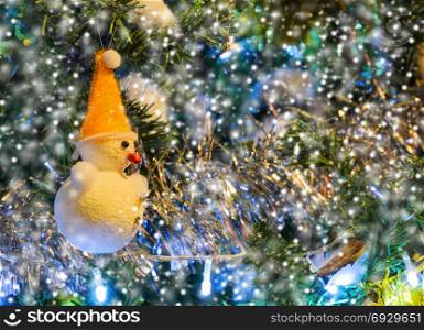 Decorated snowman on Christmas tree with snowfall