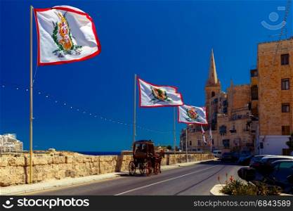 Decorated street in old town of Valletta, Malta. Festively decorated street with flags of all the Grand Masters of the Sovereign Military Order of Malta in the old town of Valletta, Malta