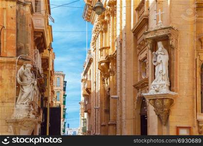 Decorated street in old town of Valletta, Malta. The traditional Maltese street stairs with corners of houses, decorated with statues of saint and Our Lady in Valletta, Capital city of Malta