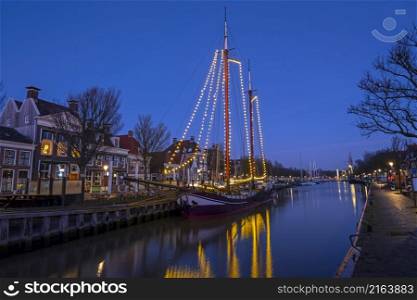 Decorated traditional sailing ship in the harbor from Harlingen in the Netherlands at sunset