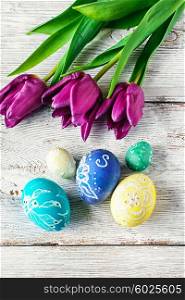Decorated with painted Easter eggs and flowers on a light background. Easter composition with flowers